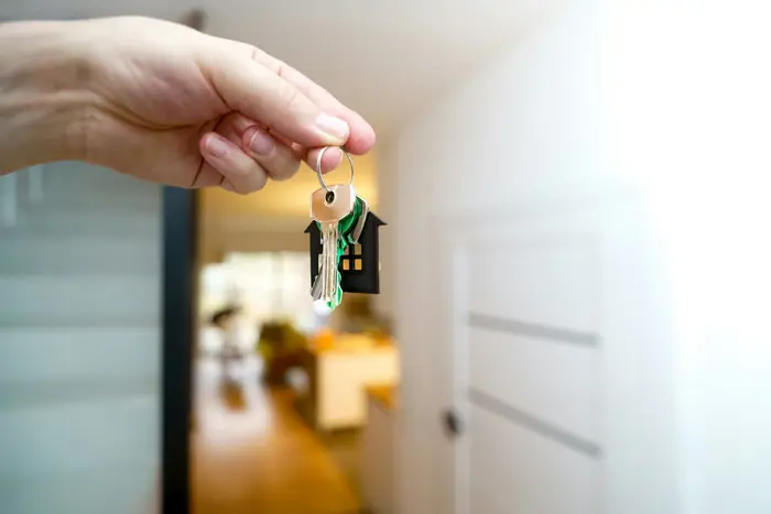A hand holding house keys in a doorway